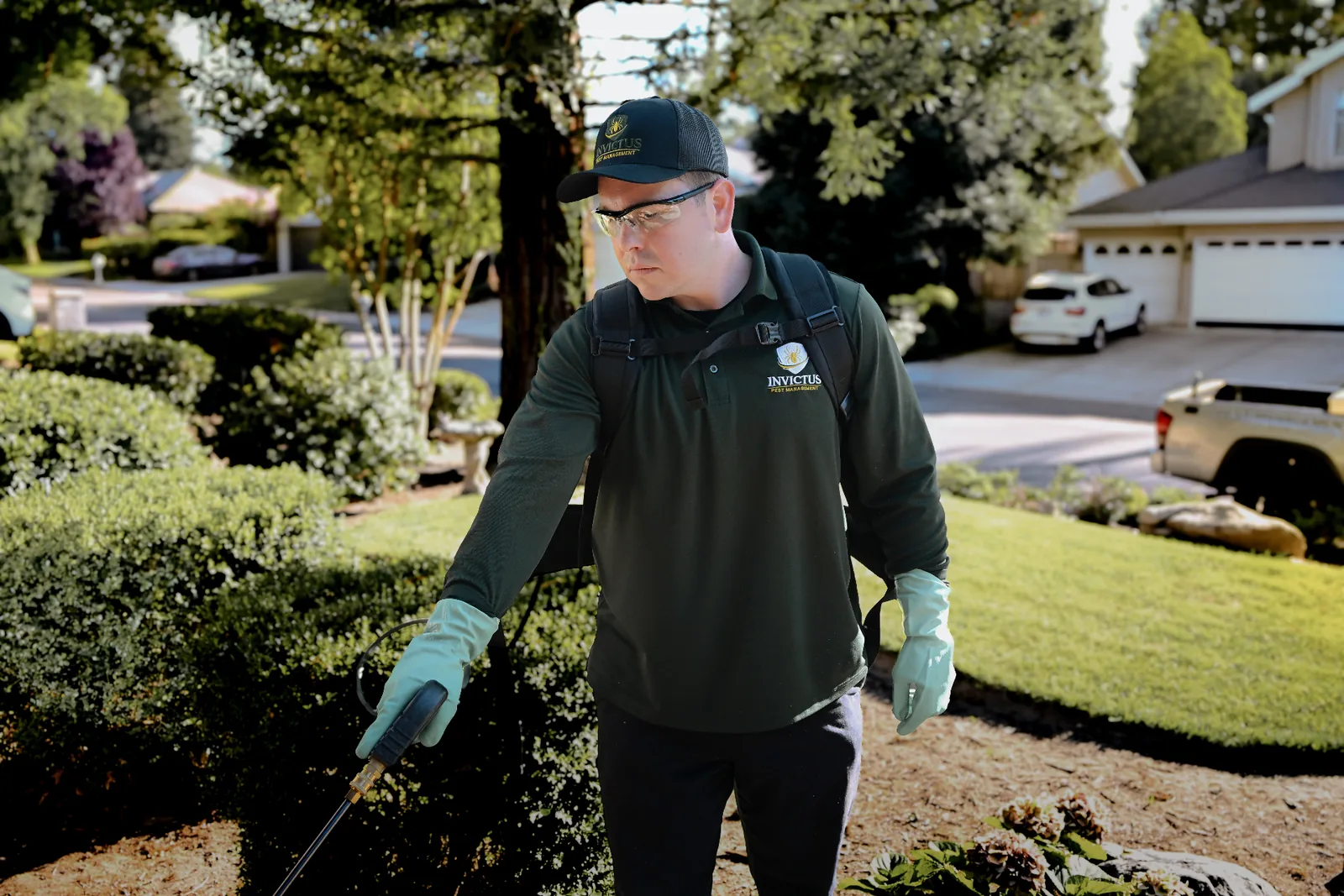 Invictus Pest Management technician in green uniform giving a thumbs up outside a home